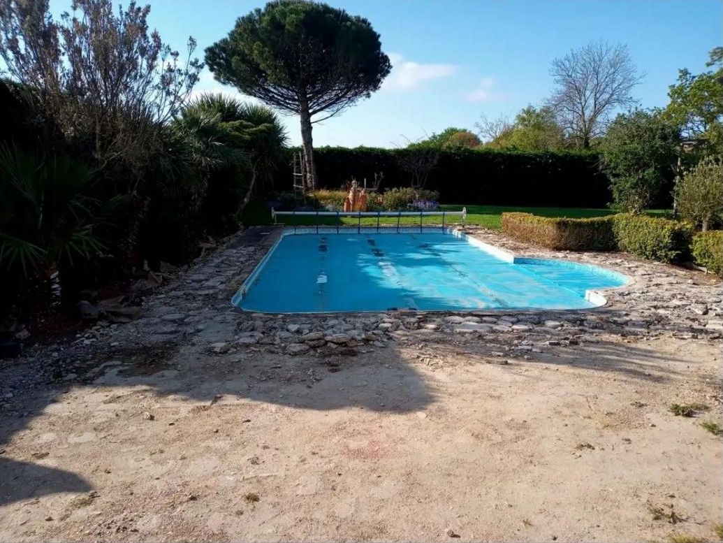 Pool sitting in bare soil and broken stone before the patio